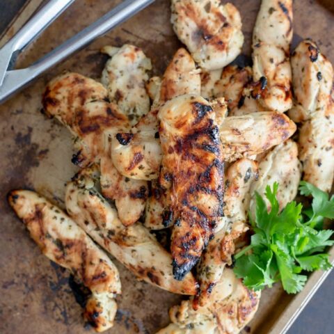 This photo features a pan piled with grilled chicken tenders.