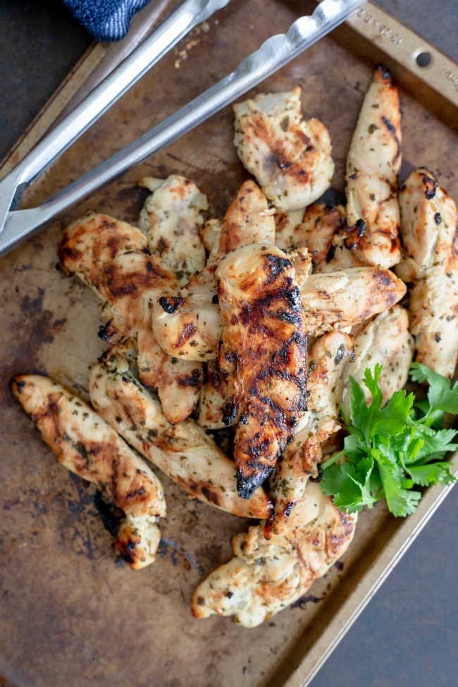 This photo features a pan piled with grilled chicken tenders.