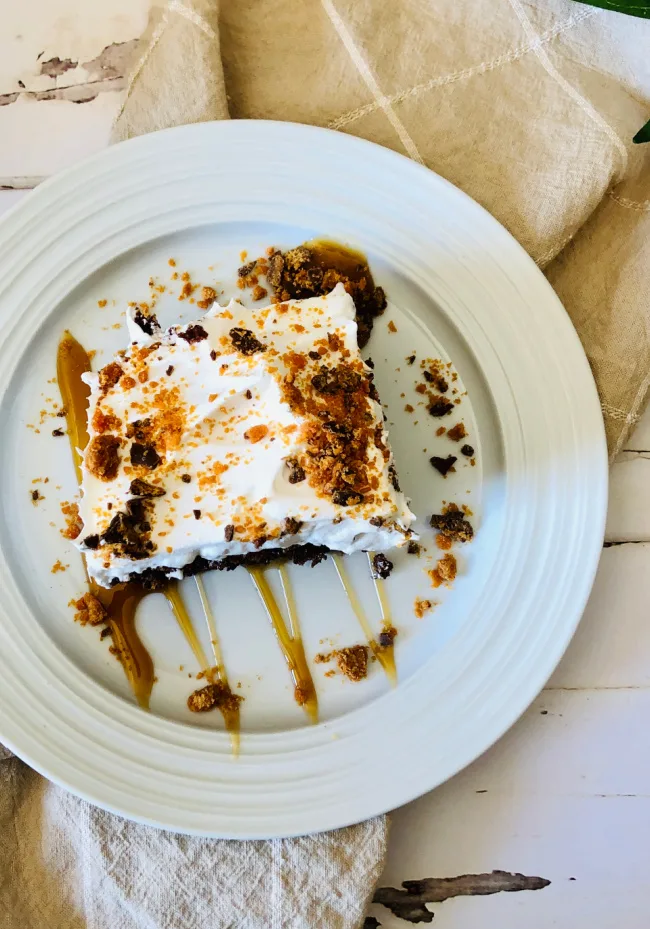 a slice of butterfinger poke cake on a white plate