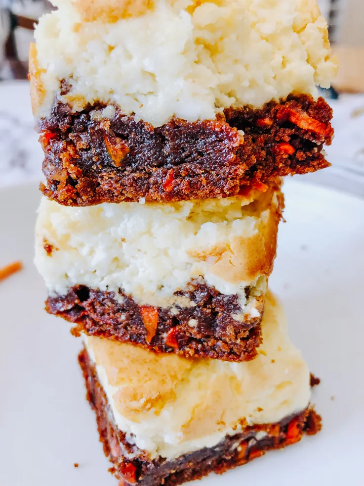 A stack of carrot cheesecake bars on a white plate