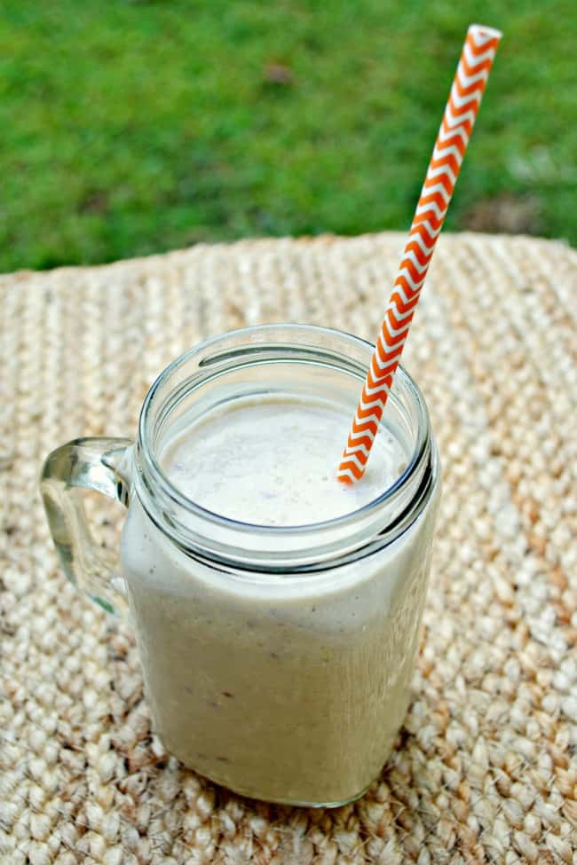 Mason mug with an apple banana and oat smoothie with a orange striped straw.