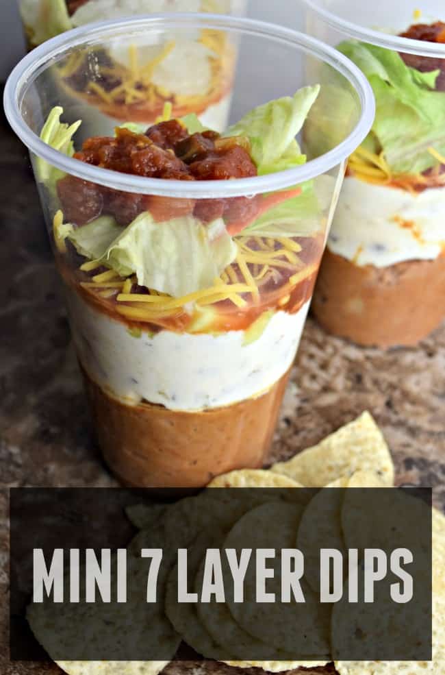 This photo is a photo of the seven layer dip in a cup. You can see all the different layers. There is a text overlay that says mini 7 layer dips.