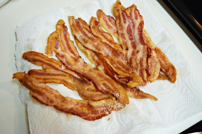 cooked  bacon on a white paper towel lined plate
