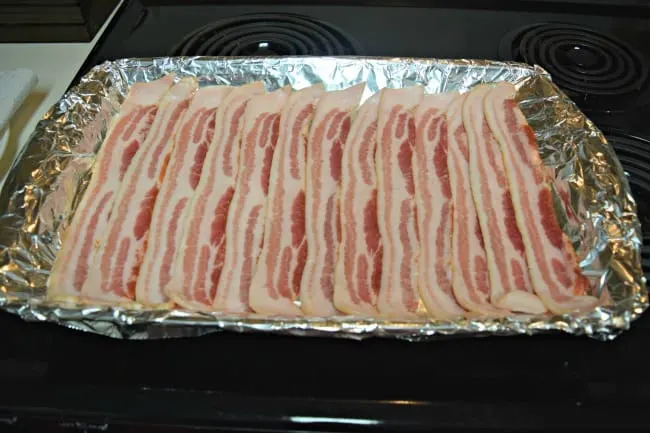 raw bacon slices on a foil-lined baking pan.