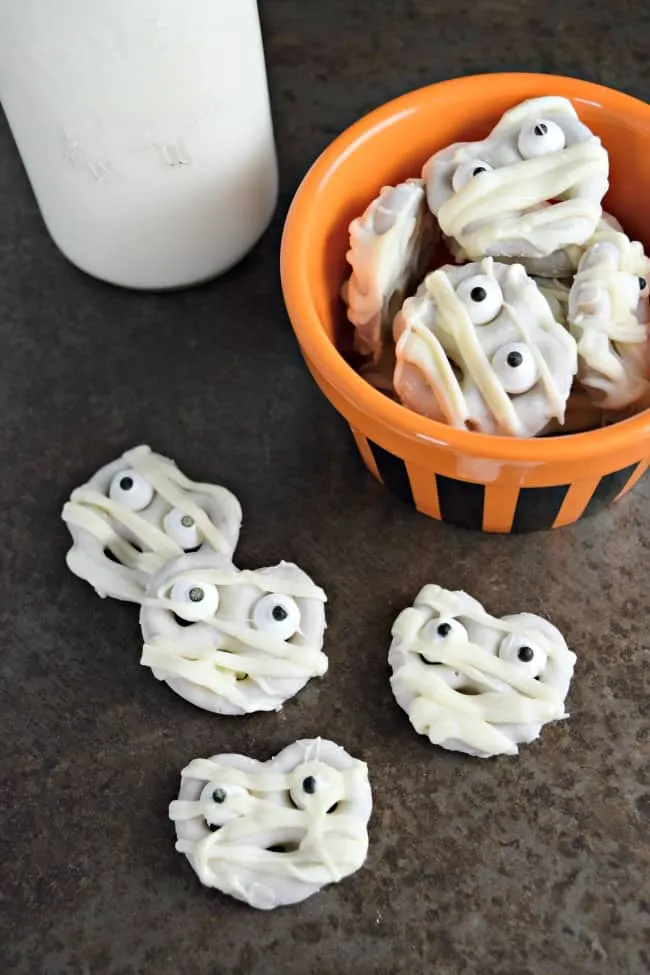 Halloween Mummy Pretzels are a yummy treat for your little goblins. The sweet of the white chocolate mixed with the saltiness of the pretzel makes for one tasty bite. Perfect for your next Halloween party!