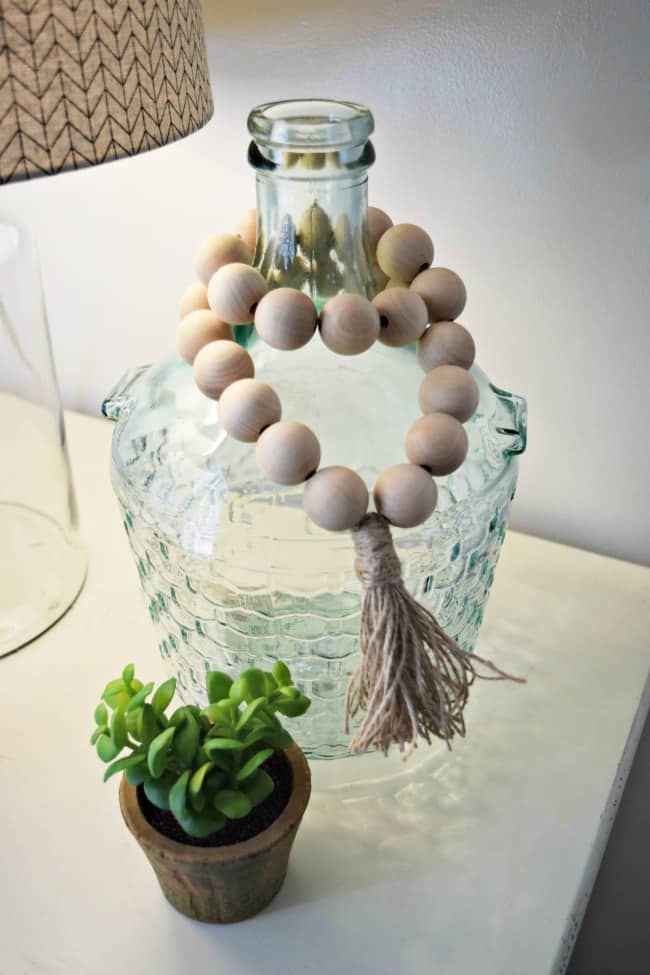 How to create your own wooden bead garlands for less than $10. Super cute and simple home decor project that only requires a couple materials.  #woodenbeads #DIY #WoodenBeadGarland