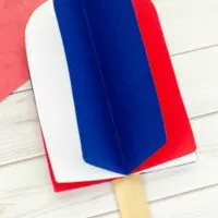 This photo features a popsicle stick popsicle craft. It uses red, white, and blue card stock paper to make a 3D popsicle.