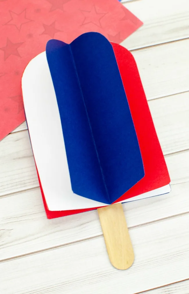 This photo features a popsicle stick popsicle craft. It uses red, white, and blue card stock paper to make a 3D popsicle. 