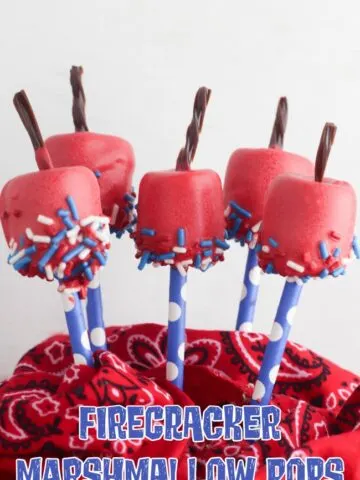 This photo features marshmallow treats that look like firecrackers. These firecracker marshmallow treats are covered in a red candy coating, dipped in red, white, and blue sprinkles, and topped with a piece of licorice for the 