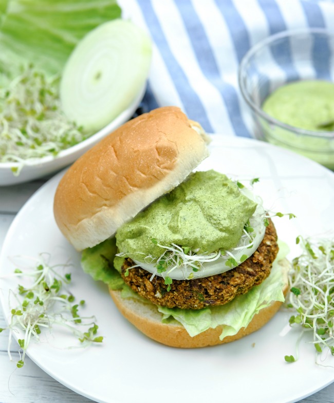 This photo features black bean burgers topped with lettuce, onion, fresh parsley, and  Chimichurri sauce.