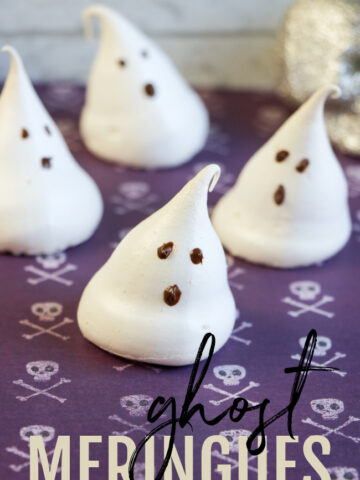 This photo features little meringue ghosts sitting on a purple Halloween skull background.