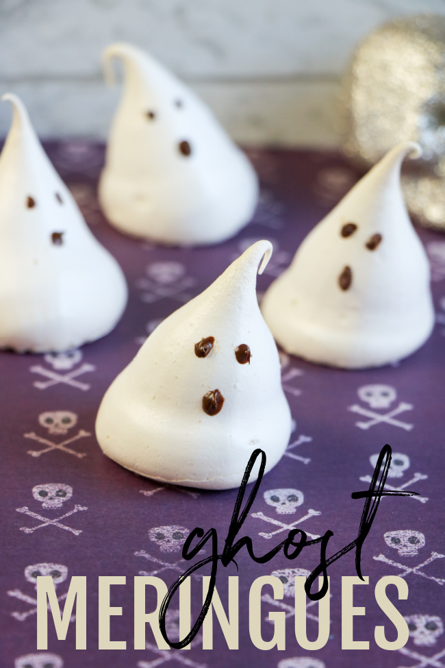 This photo features little meringue ghosts sitting on a purple Halloween skull background.