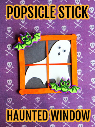 This image features a Halloween craft for kids at looks like a popsicle stick haunted window. It is laying on top of Halloween skull craft paper.