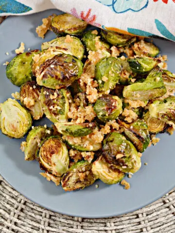 This photo features a blue plate filled with Air Fryer Brussel Sprouts.