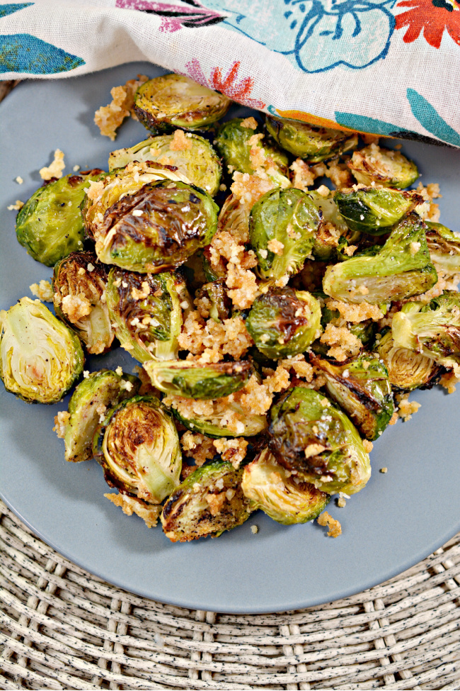 This photo features a blue plate filled with Air Fryer Brussel Sprouts.