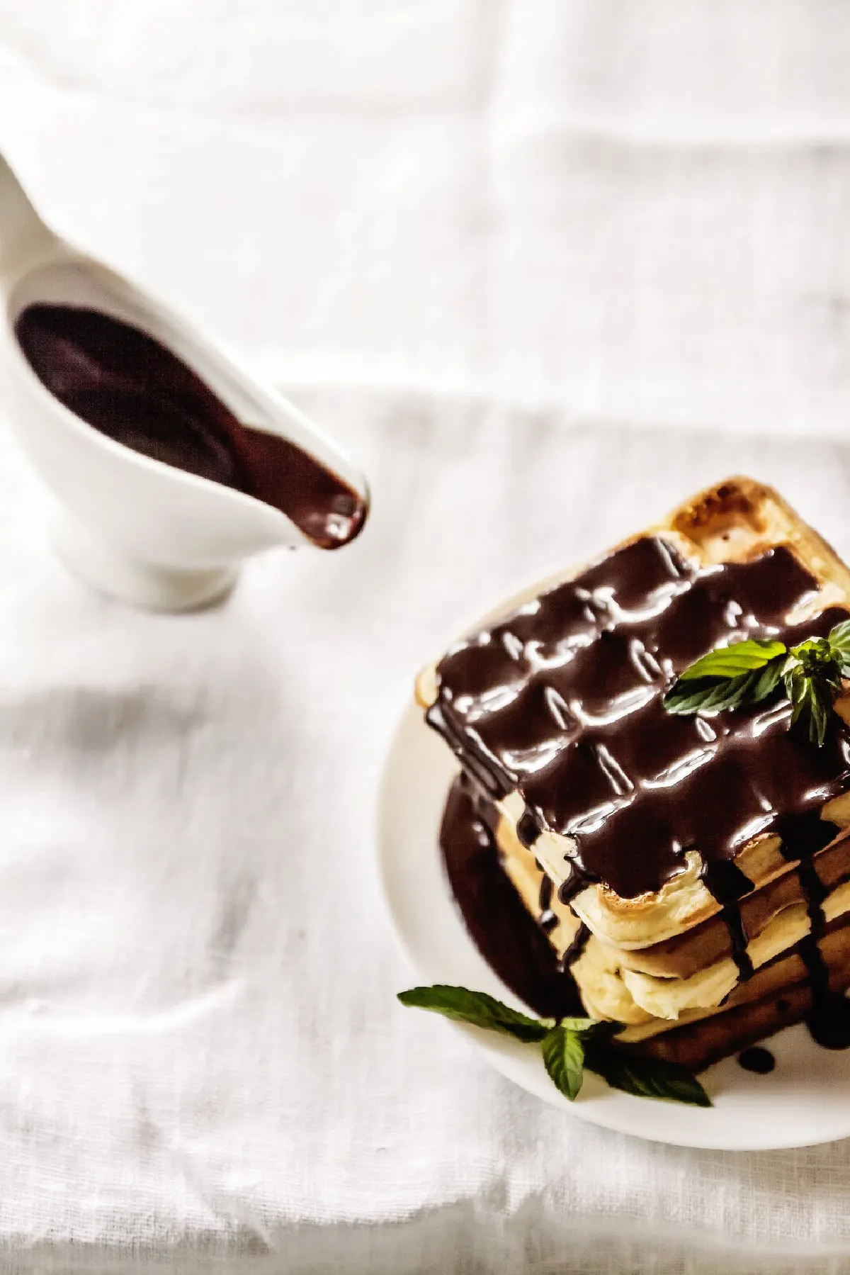 Chocolate gravy poured on top of stacked waffles and a white gravy boat set to the side.