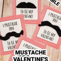 This photo features a wooden background with printed mustache valentines for kids that say I mustache you to be my Valentine.