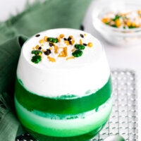 This photo features a glass cup of green jello mixed in with whipped topping.