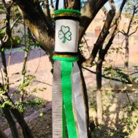 This photo features a completed St. Patrick's Day Windsock Toilet Paper Roll Craft hanging in a tree ready to catch the breeze from the wind.