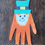 A crafted handprint leprechaun card on a wood background