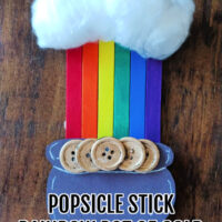 a crafted popsicle stick rainbow craft on a wood background