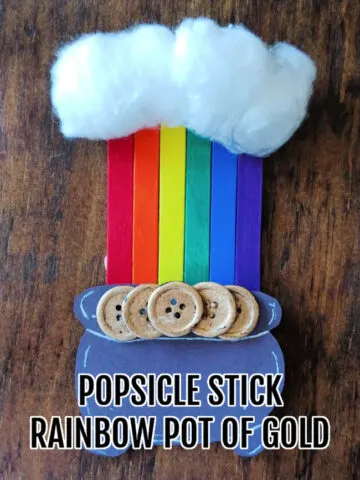 a crafted popsicle stick rainbow craft on a wood background