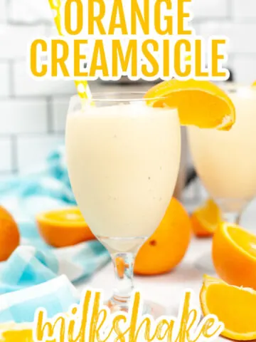 Orange Creamsicle Milkshake in a champagne style glass with a straw and slice of orange on the side.