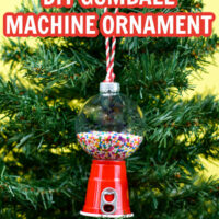 DIY Gumball Machine Ornament hanging on a green Christmas tree. The ornament is made from a mini red solo cup and a plastic clear ornament.