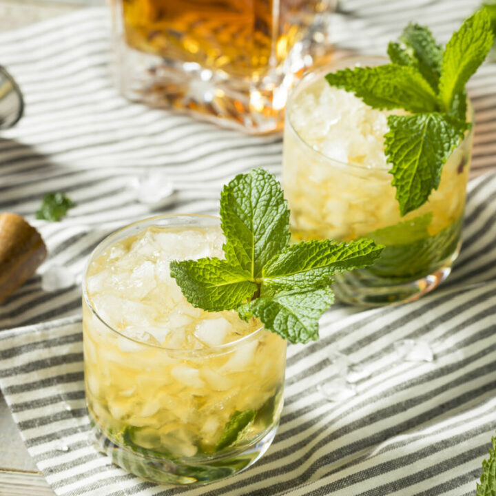 2 glasses of mint julep on a striped kitchen towel garnished with mint