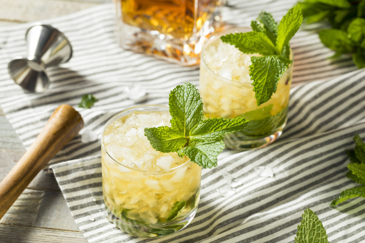 2 glasses of mint julep on a striped kitchen towel garnished with mint