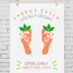 Carrot Footprint Art hung with clothespins on a white brick background