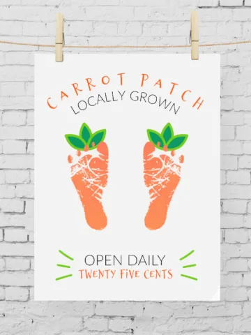 Carrot Footprint Art hung with clothespins on a white brick background