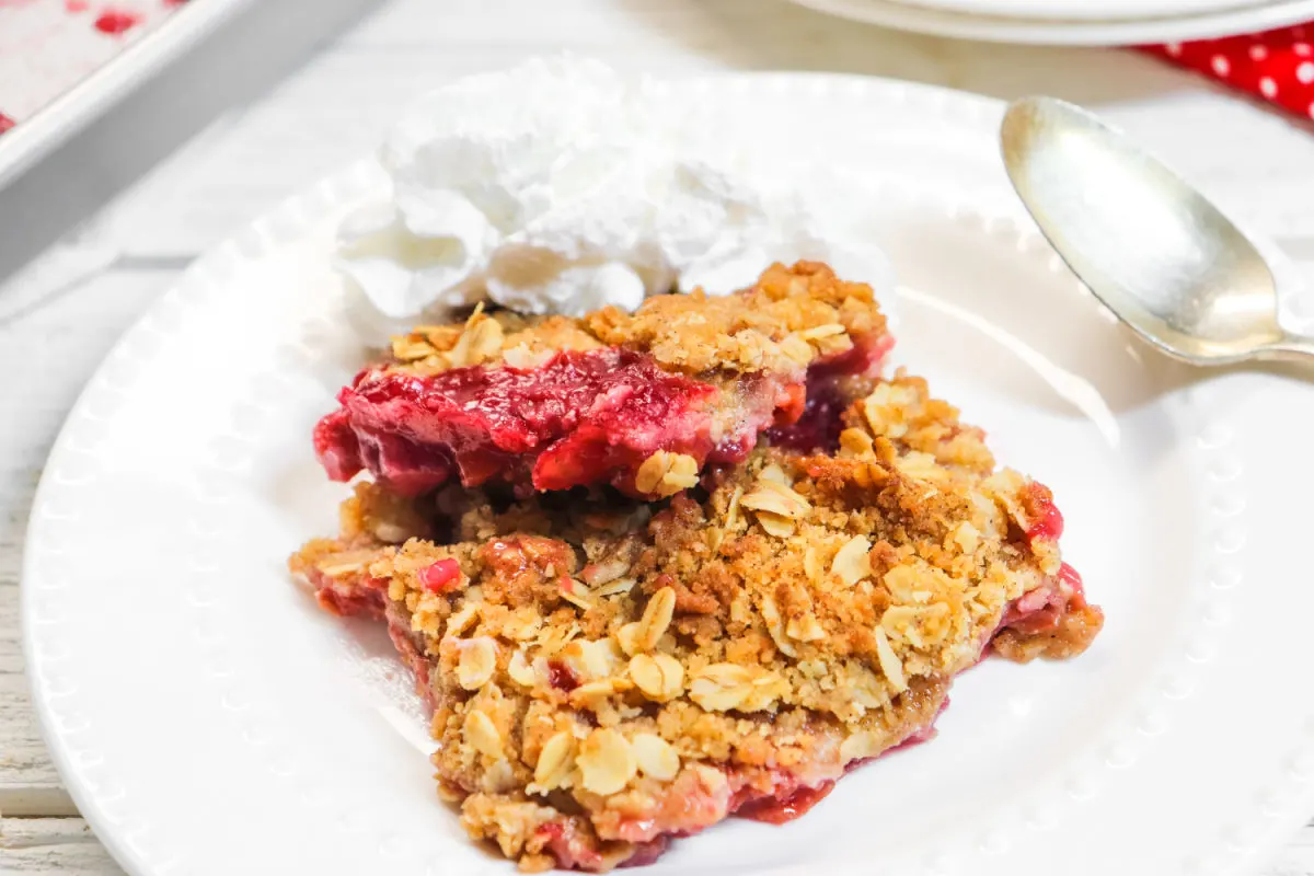 White plate of cherry crisp recipe with a spoon on the side