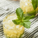 2 glasses of mint julep recipe on a white and gray striped tea towel