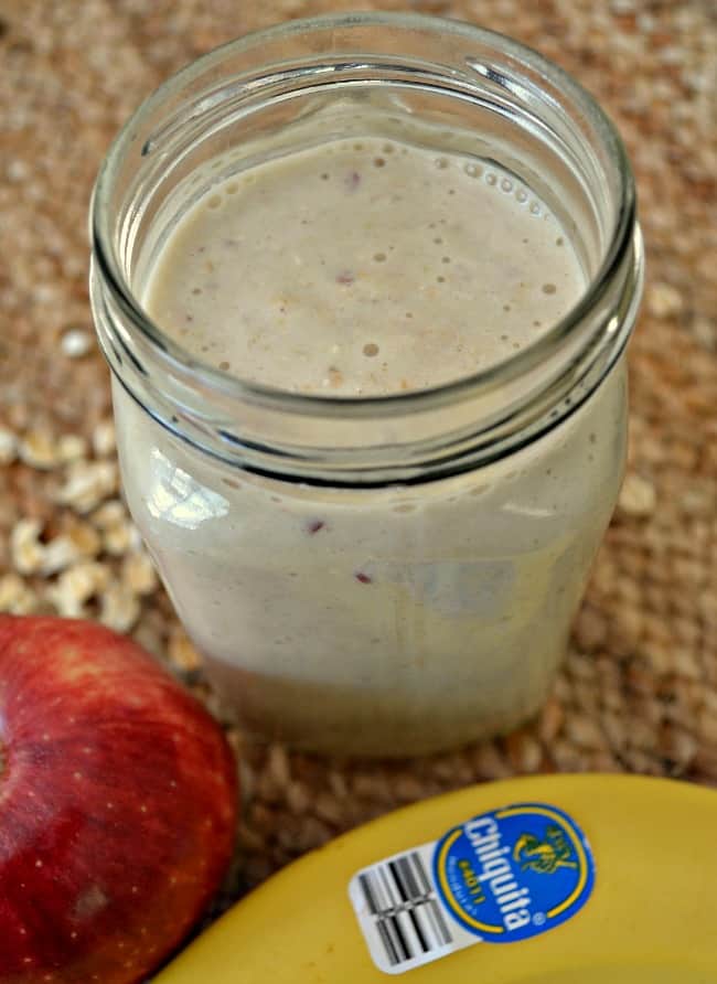 glass jar of apple banana oat smoothie on a jute texture background