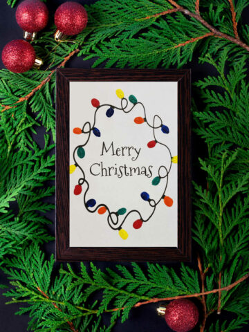 Fingerprint Christmas Lights Printable in a black frame on a Christmas background