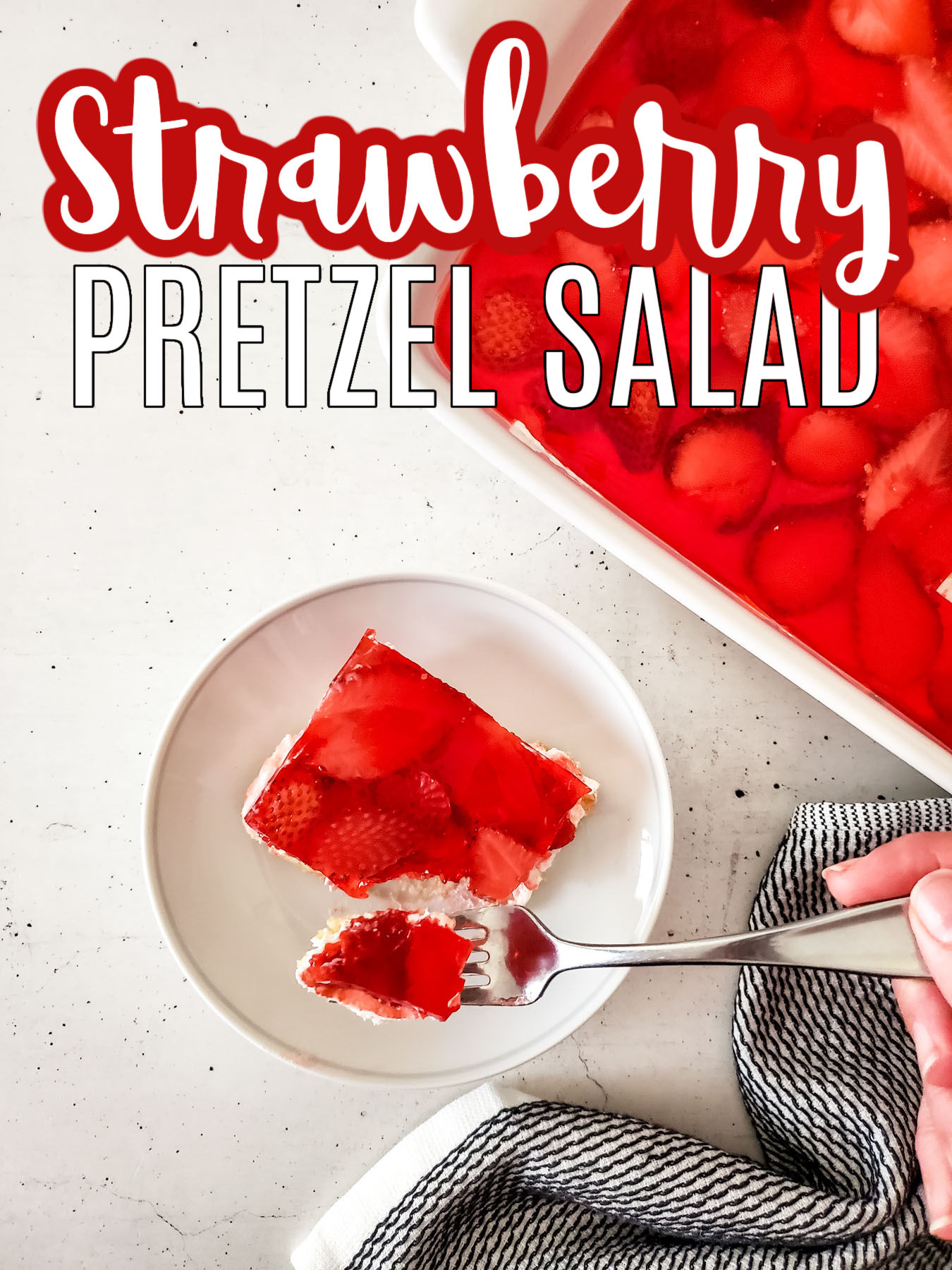 A cut piece of Strawberry Pretzel Salad on a white plate with leftovers in a white casserole pan.