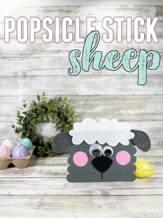 Popsicle Stick Sheep Craft with a wooden background and speckled egg props