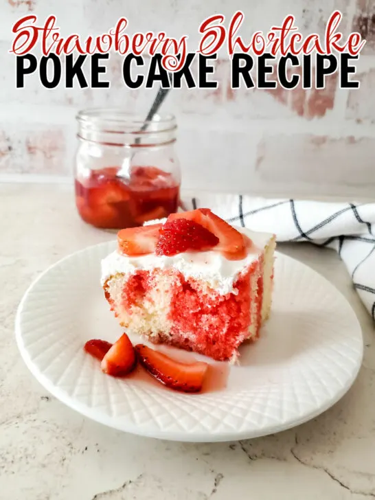 Strawberry Shortcake Poke Cake on a white plate with the brick background and a jar of strawberry topping