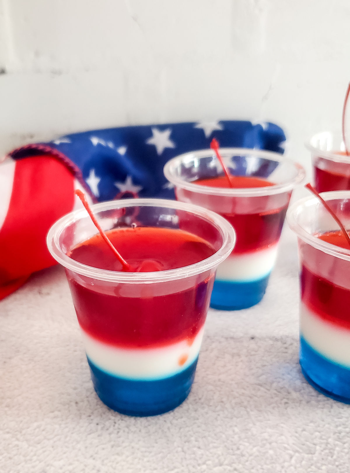 Red White and Blue Jello Shots on a marble counter with a flag in the background