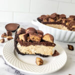 Slice of Reese's Peanut Butter Cup Pie sitting on a white plate in the foreground of the entire pie.