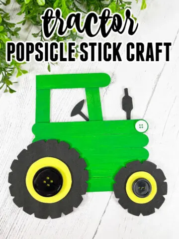 Green painted popsicle stick tractor craft on a wooden background.